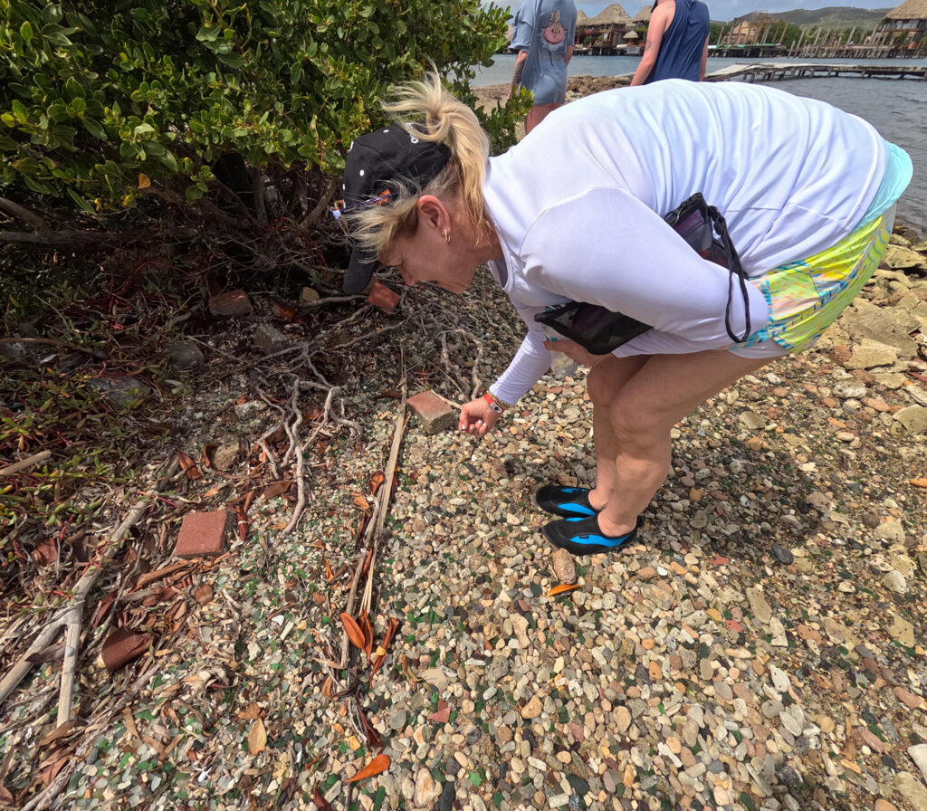 A tourist picks sea glass from the ground during a Sea Glass Island Aruba exploration.