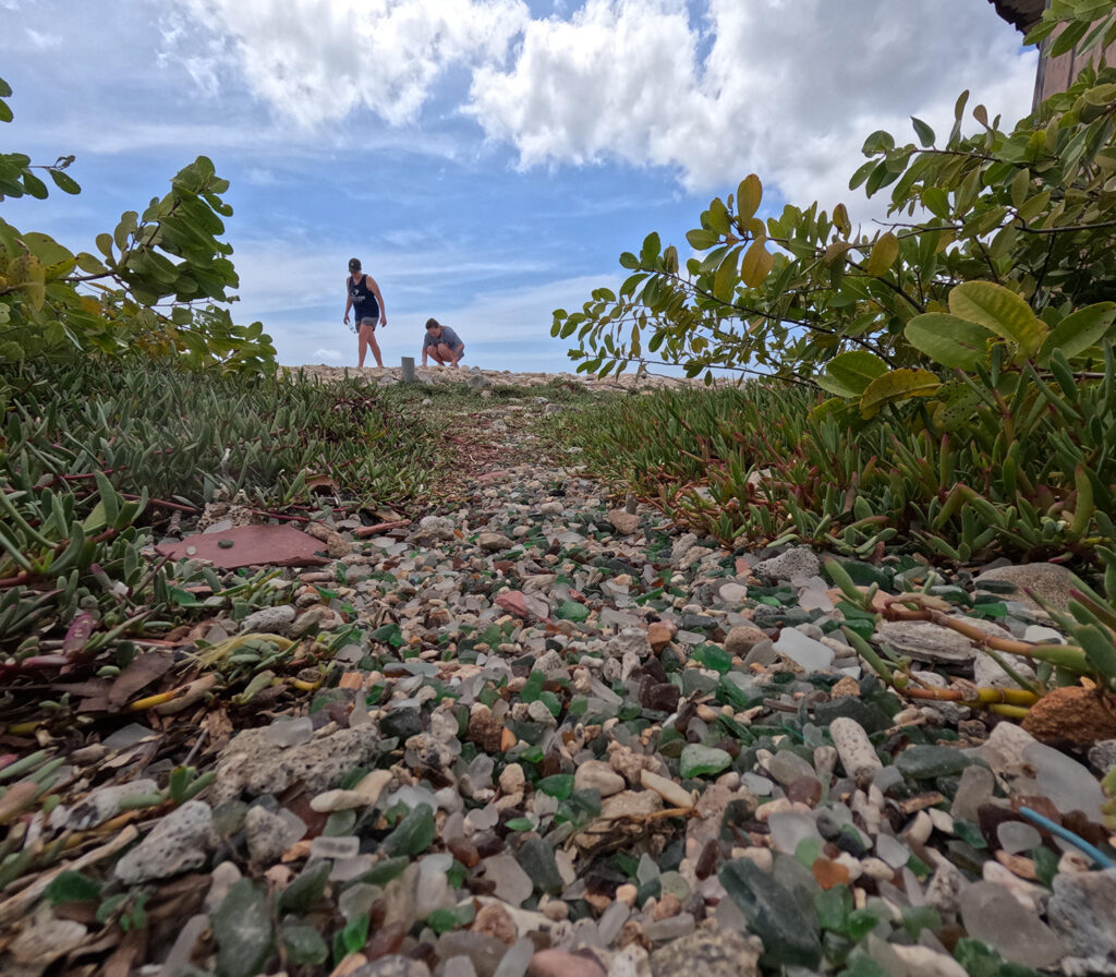 A trail of sea glass and coral leads to a group of adventurers exploring Sea Glass Island in Aruba.