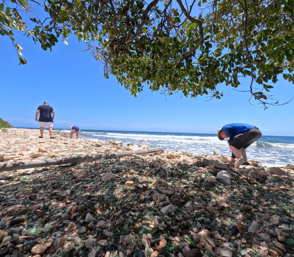 Tourists search for sea glass along the coastline of Sea Glass Island Aruba during a guided adventure.